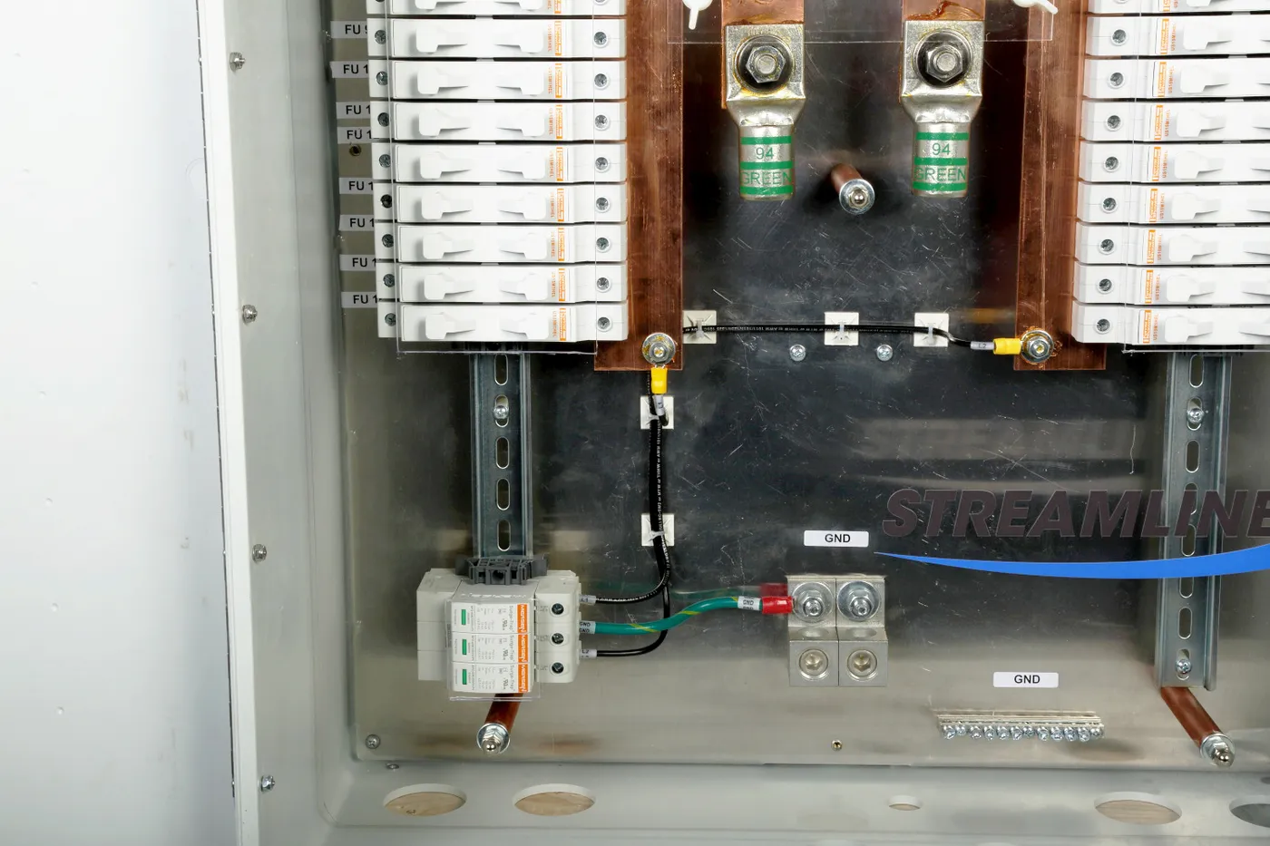 Inside a Streamline solar combiner box: rows of fuse holders, copper bus bars with output lugs, a surge protective device and ground bars